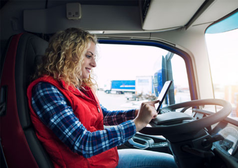 Photo of female truck driver using tablet sitting in driver seat of truck